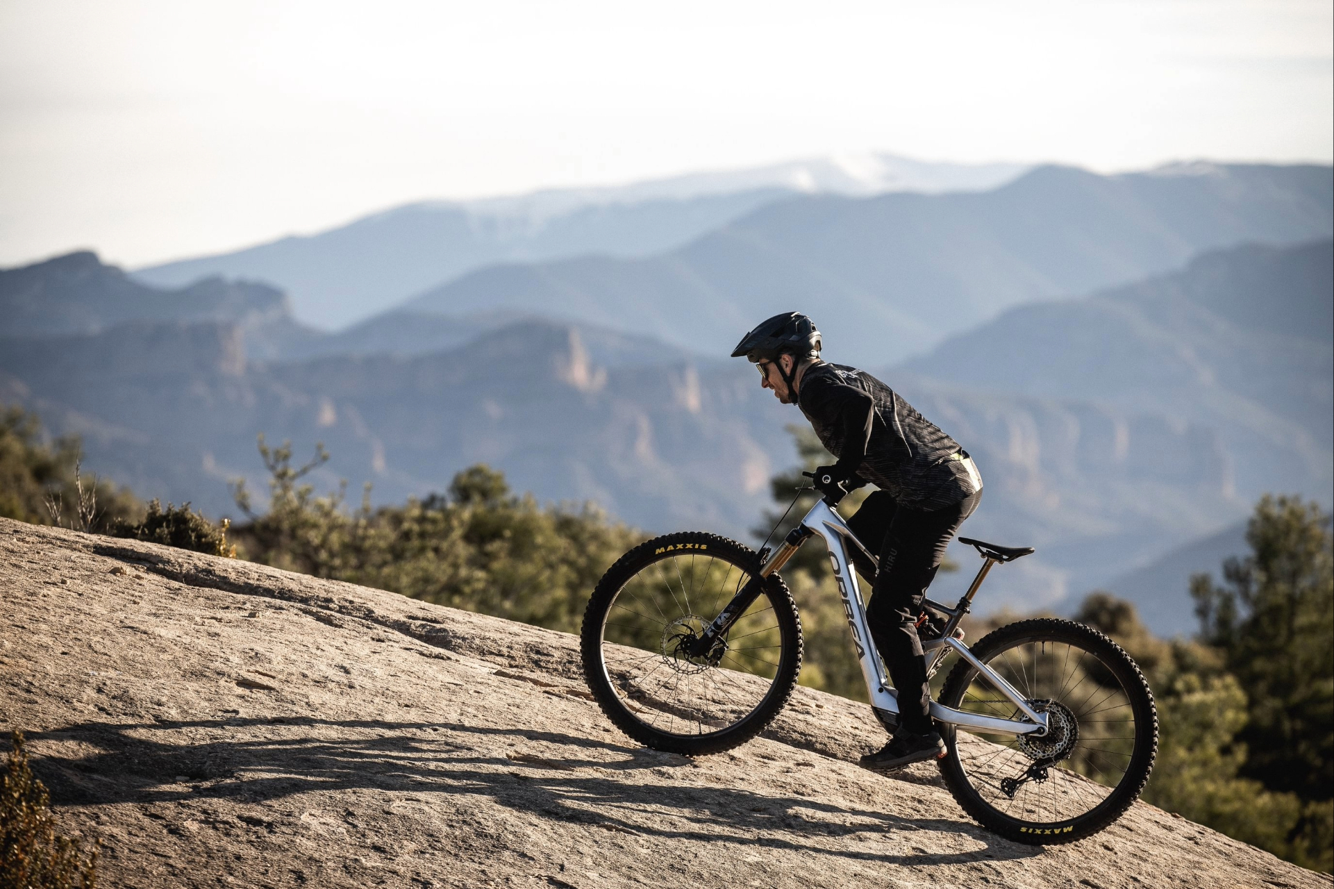 Fokussierter Radfahrer in Schwarz auf silbernem Mountainbike am Berggrat