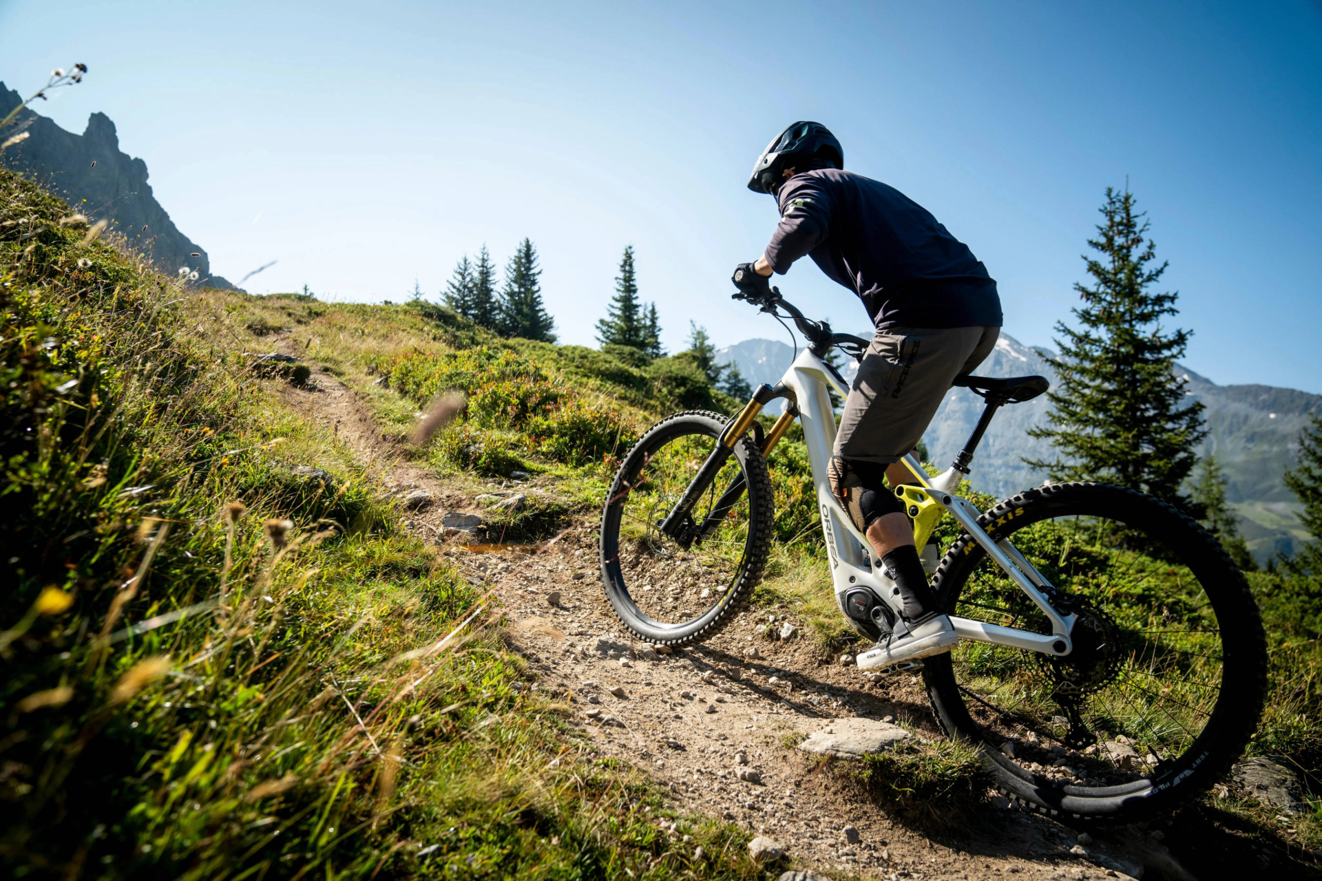 Konzentrierter Radfahrer in schwarzem Helm auf gelbem Mountainbike am Hang